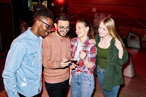 A group of friends looking at a phone, representing shared experiences and collective voyeurism.