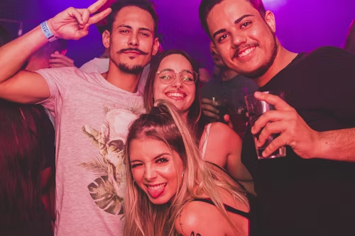 People at a club with purple lighting, representing the immersive and degenerate atmosphere.