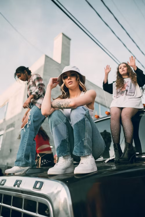 Three people on a car, one with hands up, representing a rebellious and viral moment.