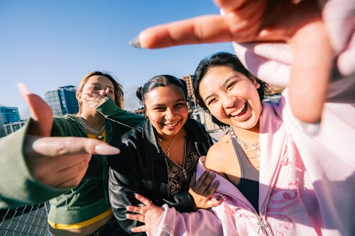 Three young women taking a wide-angle selfie, representing viral social media buzz.