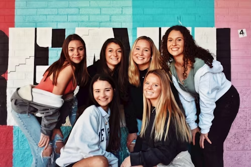 A group of young women posing in front of a graffiti wall, representing the artistic and rebellious spirit.