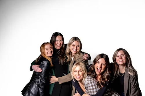 A group of women laughing and embracing, representing the shared pleasure and community.